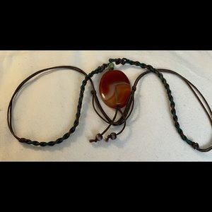 Pinky red stone on the braided string adjustable at the back by pulley knots